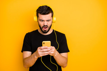 Sticker - Portrait of surprised funky guy want listen music search playlist on his smartphone find sound track dislike songs grimace wear casual style clothing isolated vivid color background