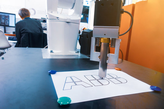 Robot outlines lines of letters with a marker.
