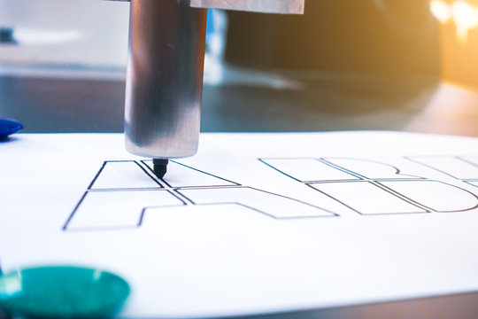 Robot outlines lines of letters with a marker.