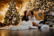 Lesbian Couple Kisses Against Background Of Christmas Decorations And Retro Car.