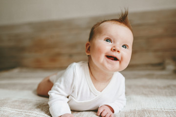 Happy infant baby crawling on bed smiling adorable child ginger hair family lifestyle 3 month old kid positive emotions