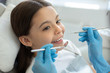 © Afshar Tetyana - smiling client at dental procedure, dentist using dental instruments in modern dental clinic