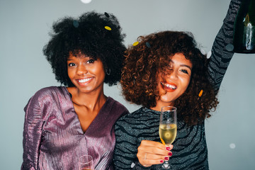 Portrait of Happy Two Young Beautiful African American friends toasting the champagne glasses with each other. Celebrating a Christmas holidays.