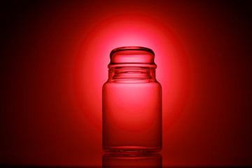 Empty glass jar on a red and black background