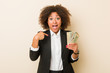 © Asier - Young african american woman holding dollars surprised pointing at himself, smiling broadly.