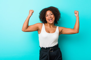 Young african american woman showing strength gesture with arms, symbol of feminine power