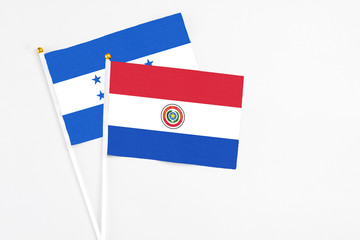 Paraguay and Honduras stick flags on white background. High quality fabric, miniature national flag. Peaceful global concept.White floor for copy space.
