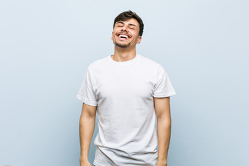 Young caucasian man wearing a white tshirt relaxed and happy laughing, neck stretched showing teeth.