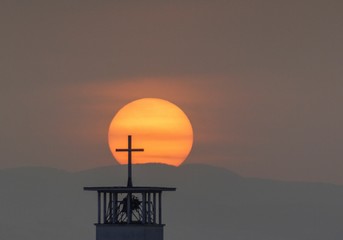 Wall Mural - Beautiful shot of a cross sculpture with the breathtaking view of sunset in the background