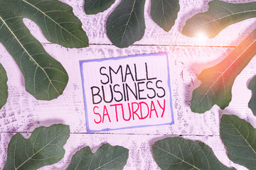 Handwriting text Small Business Saturday. Conceptual photo American shopping holiday held during the Saturday Leaves surrounding notepaper above a classic wooden table as the background