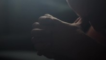 Extreme Close-up Of Man Clasping Hands Together In Dark Room