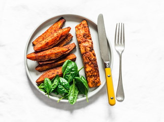 Crispy spice crust baked salmon with sweet potato and spinach - healthy balanced lunch on light background, top view