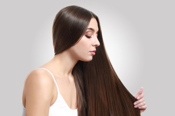 Wall Mural - Beautiful woman with healthy long hair on light background