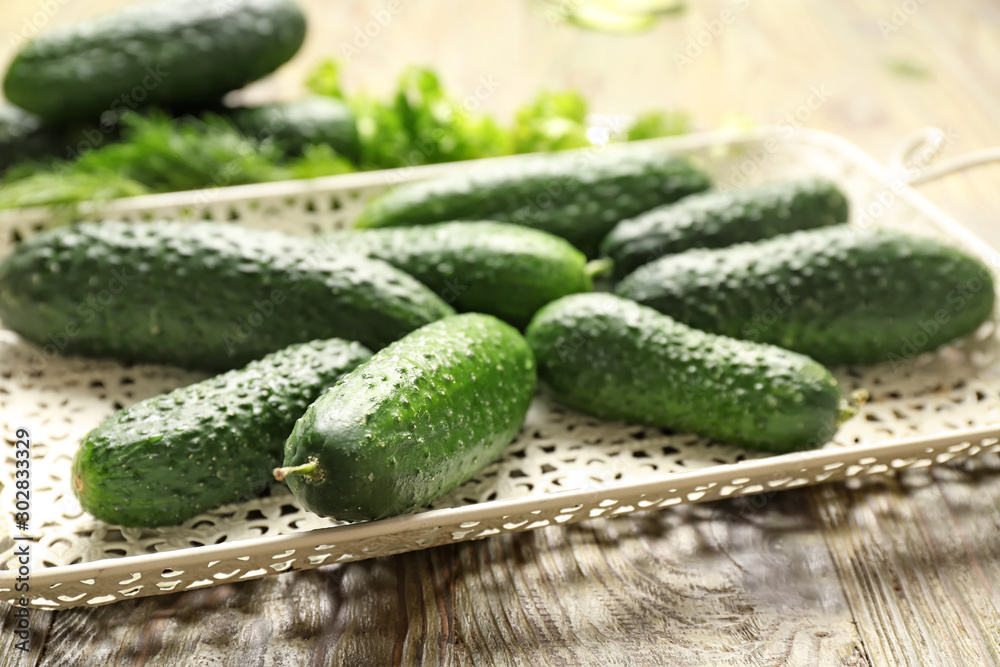 Tray with fresh cucumbers on wooden table