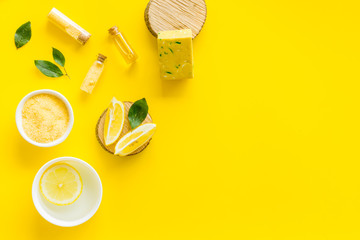 Lemon cosmetics. Cleansing tonic and handmade soap on yellow background top view frame space for text