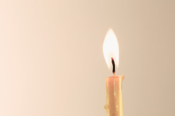 burning yellow candle on warm background