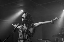 A Female Musician Is Viewed From A Low Angle As She Sings And Performs With Hands Raised And Closed Eyes, In Black And White With Copy Space