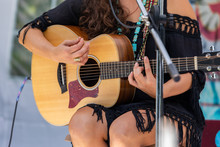A Close Up View On Musician Woman Playing The Guitar, Hands Of Female Guitarist On Outdoor Stage During A Live Music Gig In Nature