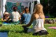 back view of blonde girl with a diverse group of people enjoying outdoor meditation session during a woodland spiritual gathering