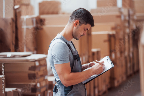 Fotomural Storage worker in uniform and notepad in hands checks production