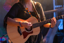 Close-up View Of Musician Woman Playing Guitar On The Stage, Female Guitarist Hands During Night Live Music Performance
