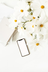 Wall Mural - Business, freelance, blogger concept. Mock up, empty, copy space. Mobile phone on white table with daisies and notebooks.