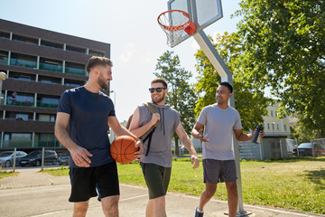 Wall Mural - sport, leisure games and male friendship concept - group of men or friends going to play basketball outdoors