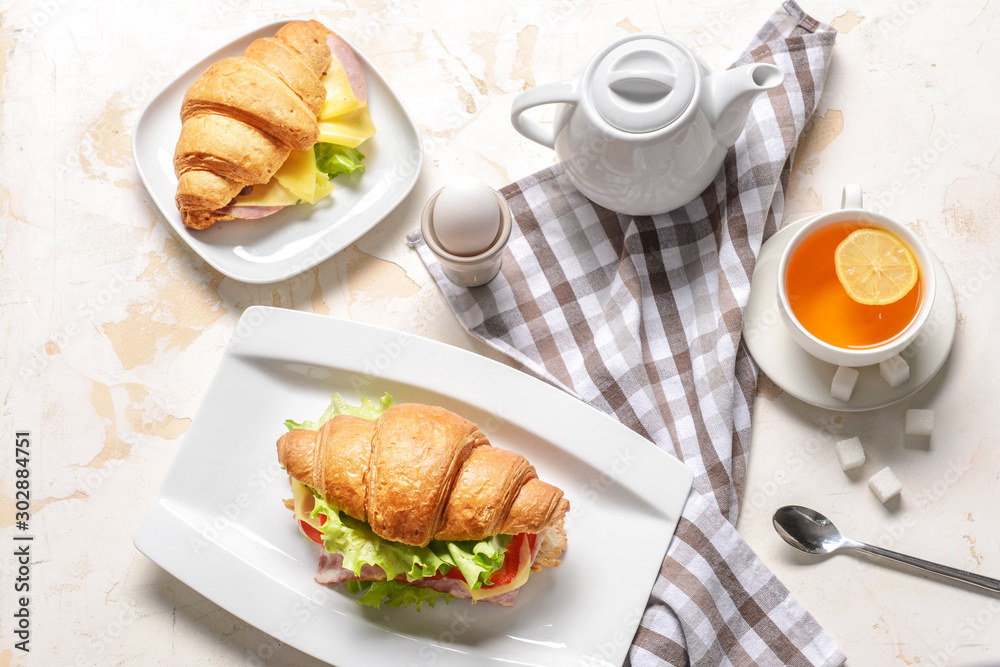 Tasty croissant sandwiches with tea on white background