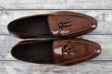 Brown classic loafers with tassels stand on a wooden stand