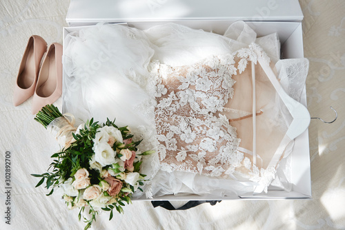 Fotomural Luxury wedding dress in white box, beige women's shoes and bridal bouquet on bed, copy space