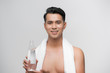 © makistock - Portrait of young man drinking water with towel around neck over white background
