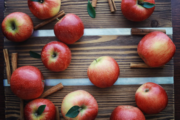 Fresh apples on a wooden board. Harvest of red apples. Fruits and cinnamon on the table.