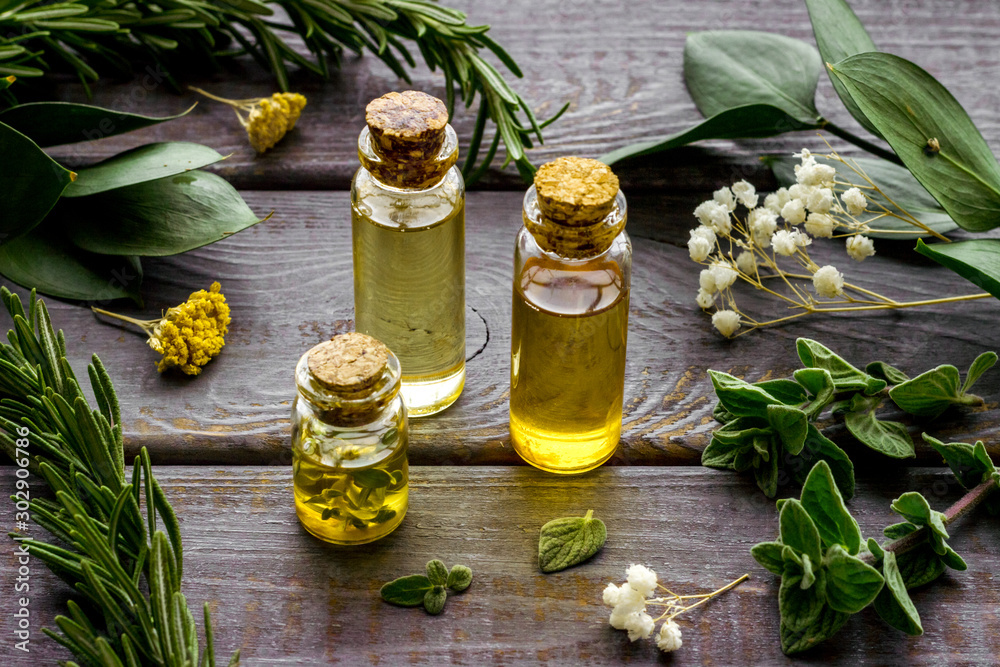Aromatherapy. Essential oils in small bottles near fresh herbs on dark wooden background - obrazy, fototapety, plakaty 