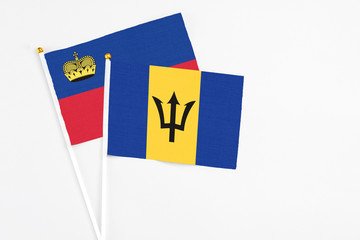 Barbados and Liechtenstein stick flags on white background. High quality fabric, miniature national flag. Peaceful global concept.White floor for copy space.