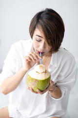 Asian cute girl relax with coconut  drink in white room, lifestyle concept.