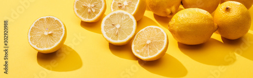 ripe-cut-and-whole-lemons-on-yellow-background-panoramic-shot