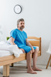 © LIGHTFIELD STUDIOS - patient in medical gown sitting on bed and looking away in hospital