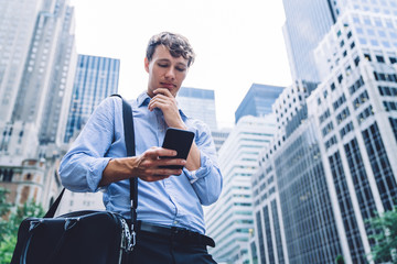 Contemporary worker standing wiyh phone in hands in magapolis