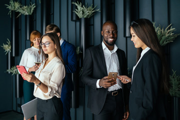 Group of modern diverse employees with smartphones