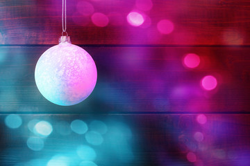 Wall Mural - Christmas bauble in turquoise and pink lights over wooden background