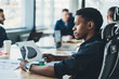 © BullRun - Pensive African American offie employee sitting at meeting table with colleagues on background