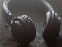 Black Wireless Headphones On A Black Textured Background. Close Up.