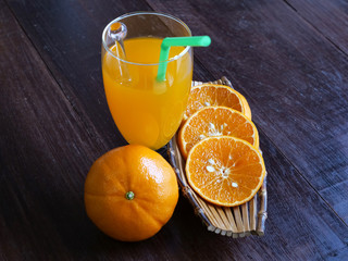 Sliced oranges and fruit juice on a wooden background