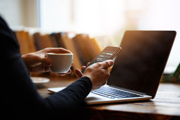 Wall Mural - a man uses internet banking on his mobile and holds a coffee cup