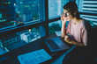 © BullRun - Young talented copywriter in stylish eyeglasses watching training webinar on laptop connected to wireless internet.Pretty skilled female employee analyzing information from network sitting in office