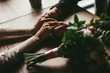 © VlaDee - Bride and groom holding hands on wooden table indoor cafe