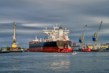 Wall Mural - large cargo ship, assisted by tugs, enters the port. Gdansk. Poland