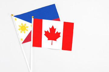 Wall Mural - Canada and Philippines stick flags on white background. High quality fabric, miniature national flag. Peaceful global concept.White floor for copy space.