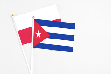 Cuba and Poland stick flags on white background. High quality fabric, miniature national flag. Peaceful global concept.White floor for copy space.