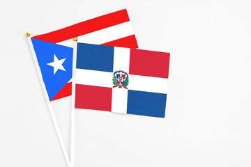 Wall Mural - Dominican Republic and Puerto Rico stick flags on white background. High quality fabric, miniature national flag. Peaceful global concept.White floor for copy space.